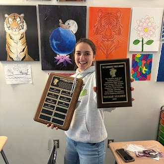 Student holding the Barnabas Tiger Award plaque